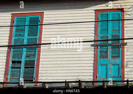 Old abandoned white wood panel house with turquoise blue doors with paint peeling off Stock Photo