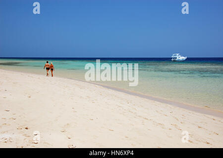 Couple walking along the beach at the turquoise red sea in egypt Stock Photo