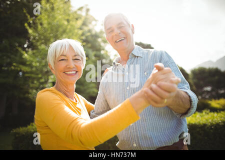 Portrait of happy senior couple dancing in park Stock Photo