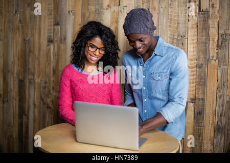 Smiling couple using laptop in cafÃƒÂ© Stock Photo