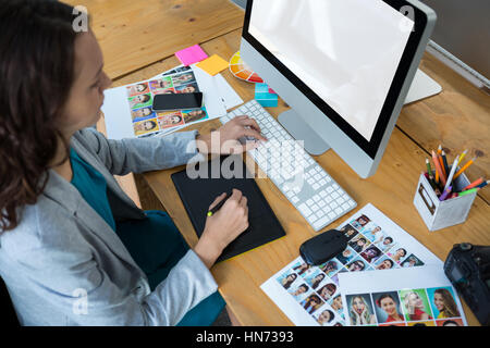 Female graphic designer using graphics tablet at desk in office Stock Photo