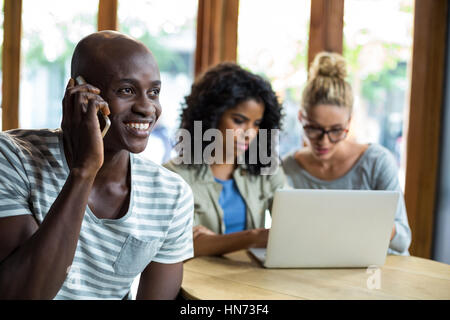 Smiling man talking on mobile phone in café