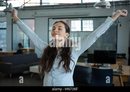 Graphic designer stretching her arms out in office Stock Photo