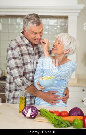 Senior woman feeding man in kitchen Stock Photo