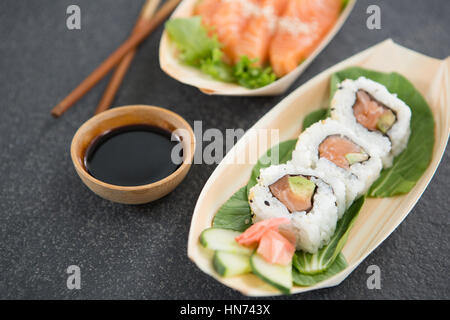 Sushi on boat shaped plate with chopsticks and sauce Stock Photo