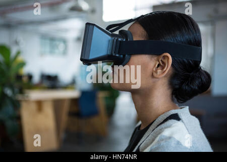 Businesswoman using virtual reality headset in office Stock Photo