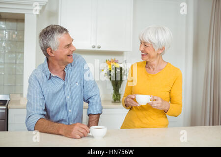 Happy senior couple interacting each other while having coffee in kitchen Stock Photo