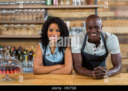 Portrait of smiling waiter and waitress leaning at counter in cafÃƒÂ© Stock Photo