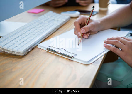 Close-up of female business executive writing on clipboard at desk in office Stock Photo