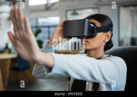 Businesswoman using virtual reality headset in office Stock Photo