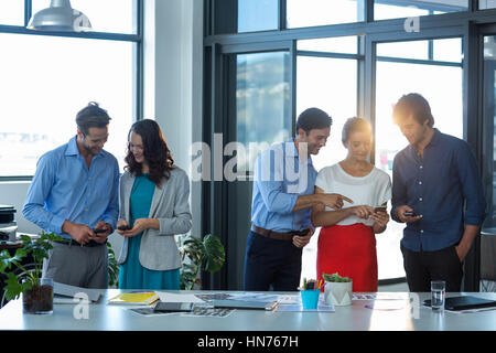 Team of graphic designers using mobile phone in office Stock Photo