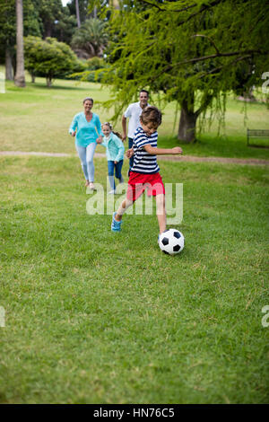 Happy family playing football in park on a sunny day Stock Photo