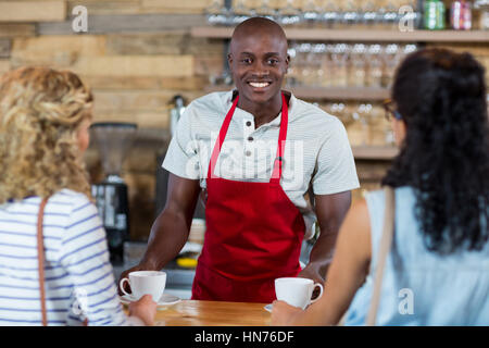 Waiter serving coffee to female customer in cafÃƒÂ© Stock Photo