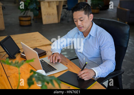 Graphic designer drawing on a graphic tablet while using laptop in office Stock Photo
