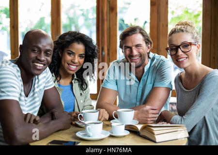 Portrait smiling friends with coffee cups on table in cafÃƒÂ© Stock Photo