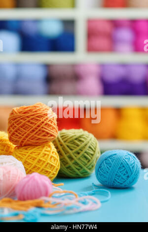 Knitting yarn on blue table against blurred background. Close up of multi colored woolen balls. Stock Photo