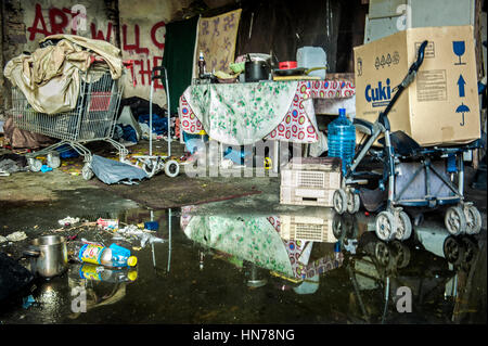 At the south wall of the central hall of the former soap factory Mira Lanza, a mural of the French street artist Seth is covered by a shack and various objects of the homeless camped there, reflected in the water fallen from the broken roof Stock Photo