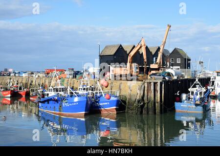 Whitstable, United Kingdom -October 1, 2016: Fishing Boats in Whitstable Harbour with warehouse in background Stock Photo