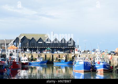 Whitstable, United Kingdom -October 1, 2016: Fishing Boats in Whitstable Harbour with row of warehouses in background Stock Photo