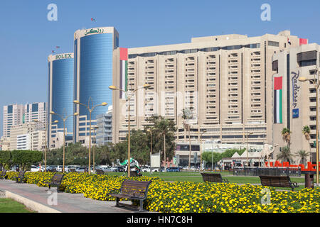 DUBAI, UAE - DEC 6, 2016: Buildings in Deira at the Dubai Creek. Flowers and benches at the creek waterfront. United Arab Emirates, Middle East Stock Photo