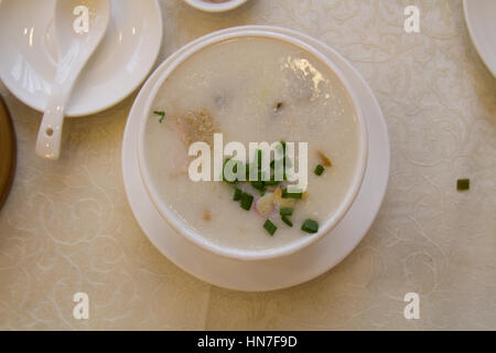 Congee or Rice porridge with coriander and spoon in a restaurant. top view. Stock Photo