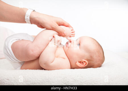 Close-up shot of three month baby girl receiving leg massage from a female massage therapist Stock Photo