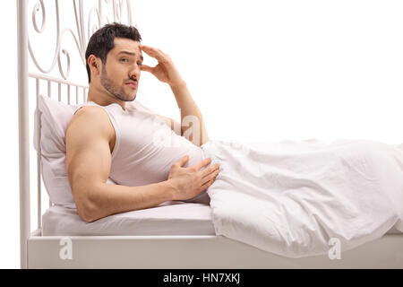 Worried guy lying in bed isolated on white background Stock Photo