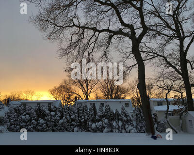 Merrick, New York, USA. 9th Feb, 2017. Sunset casts golden glow on snowy landscape in suburban Long Island home backyard. Snowstorm slams into Long Island, dumping over 12 inches of snow in banding on some areas. Winter snow storm and blizzard warnings were issued, and Gov. Cuomo urged drivers to stay off roads, due to near-whiteout conditions making visibility poor, and heavy snow and winds. Credit: Ann Parry/ZUMA Wire/Alamy Live News Stock Photo