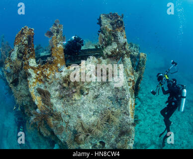 Underwater photographer posing model on bow of shipwreck. Stock Photo