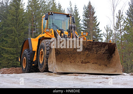 Yellow wheel loader at rural road construction site in winter. Stock Photo