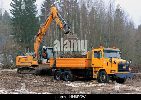 FORSSA, FINLAND - JANUARY 28, 2017: Liebherr R 918 crawler excavator loads soil onto yellow Sisu SR 332 tipping truck in winter. Stock Photo