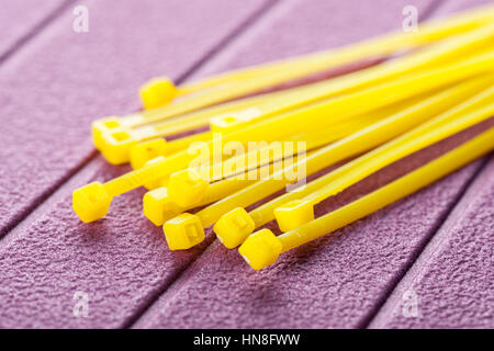 heap of yellow cable ties on purple background Stock Photo