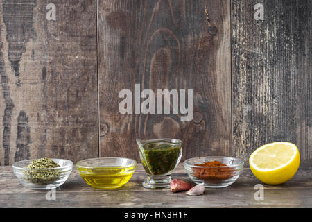 Green Chimichurri Sauce and ingredients on wooden table Stock Photo