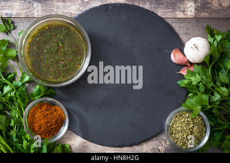 Green Chimichurri Sauce and ingredients on wooden background Stock Photo