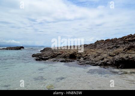Coastal rocks in the foreground ocean, clouds and horizon in the background Stock Photo