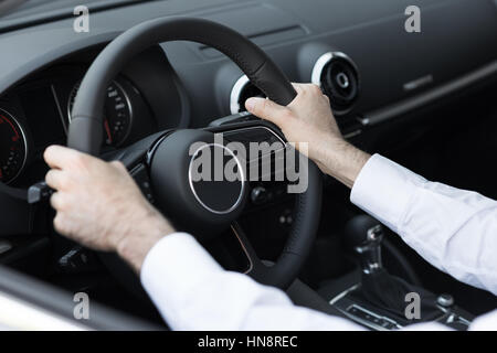 Successful businessman driving his car, hands on steering wheel close up Stock Photo