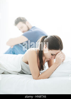 Young couple in the bedroom having relationship difficulties and arguing, the woman is crying Stock Photo
