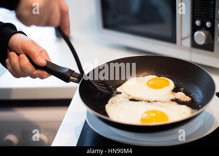 Unrecognizable man preparing fried eggs for breakfast. Close up. Stock Photo