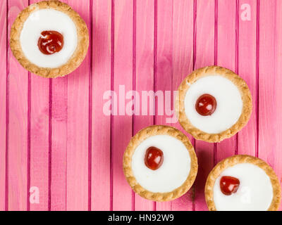 Individual Iced Bakewell Tarts On A Pink Background Stock Photo