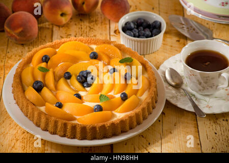Peach and Blueberry flan with black tea on table Stock Photo
