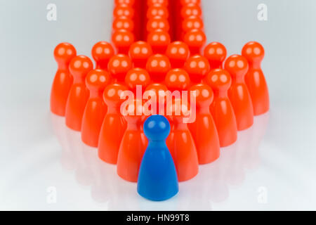 Conceptual orange game pawns and a blue play pawn as abstract display of inequality in color and number of Stock Photo