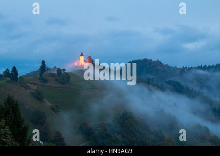 Jamnik church on a hillside in autumn, foggy weather at sunset in Slovenia, Europe Stock Photo