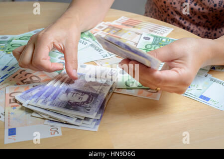 Person counting holiday currency-UK Pounds Sterling and Euros Stock Photo