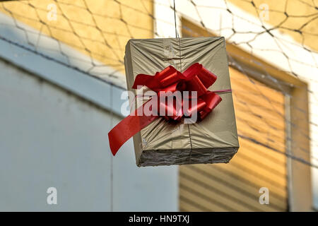 Gift boxes that hang suspended on wires and networks. Street decorations before Christmas, New Year and Valentine's Day. Stock Photo