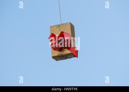 Gift boxes that hang suspended on wires and networks. Street decorations before Christmas, New Year and Valentine's Day. Stock Photo
