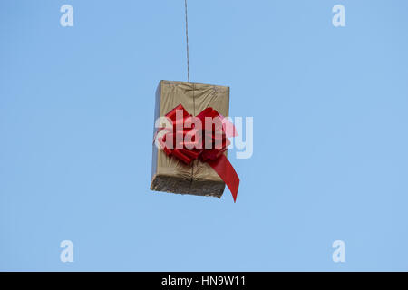 Gift boxes that hang suspended on wires and networks. Street decorations before Christmas, New Year and Valentine's Day. Stock Photo