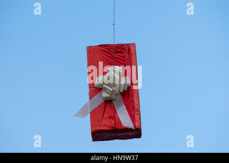 Gift boxes that hang suspended on wires and networks. Street decorations before Christmas, New Year and Valentine's Day. Stock Photo