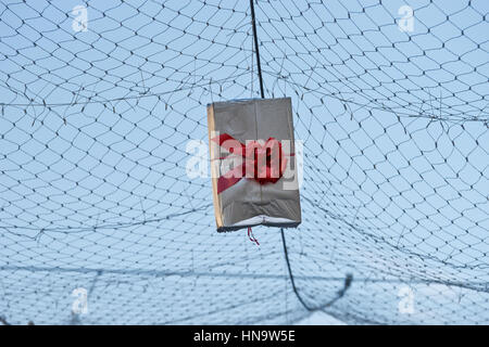 Gift boxes that hang suspended on wires and networks. Street decorations before Christmas, New Year and Valentine's Day. Stock Photo