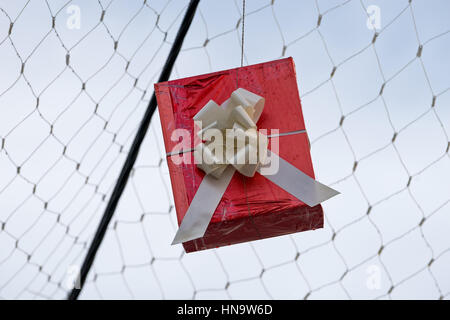 Gift boxes that hang suspended on wires and networks. Street decorations before Christmas, New Year and Valentine's Day. Stock Photo