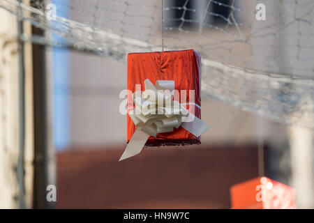Gift boxes that hang suspended on wires and networks. Street decorations before Christmas, New Year and Valentine's Day. Stock Photo